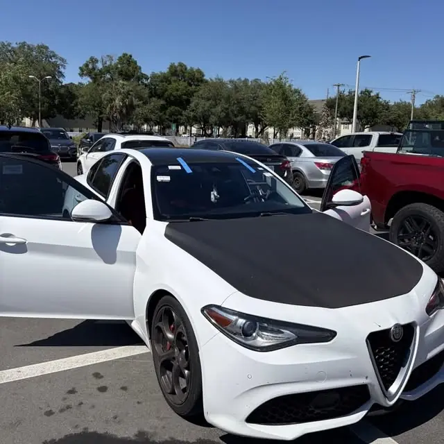 White Alfa Romeo with a protective hood cover during a mobile windshield replacement in a parking lot